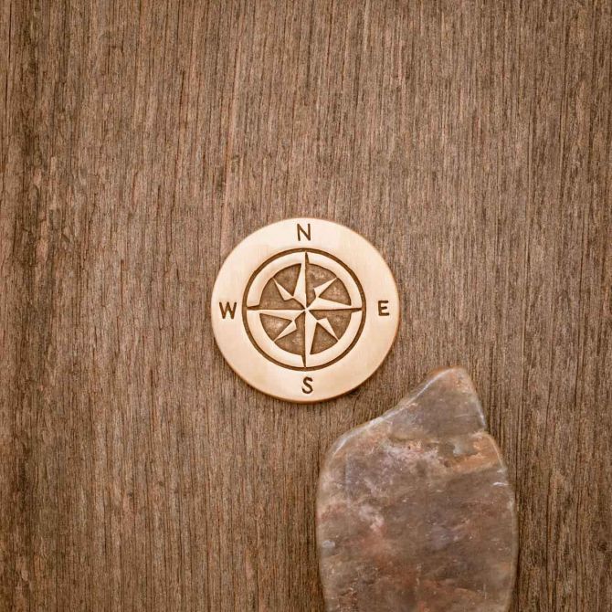 Bronze Guiding Compass Golf ball marker on wood background