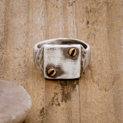 the Bonded Rivet Ring, handcrafted in sterling silver with bronze rivets and a textured finish, on a wood background